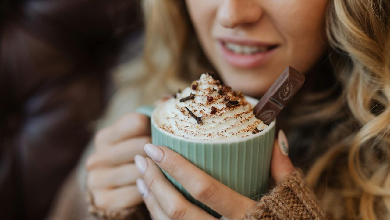 Warm up with a delicious hot chocolate topped with whipped cream and chocolate shavings in a cozy setting.
