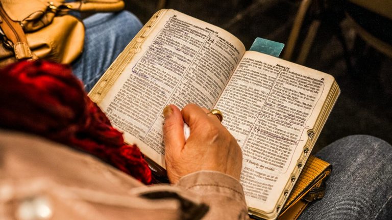 A person reading a Bible indoors, symbolizing spirituality and devotion.
