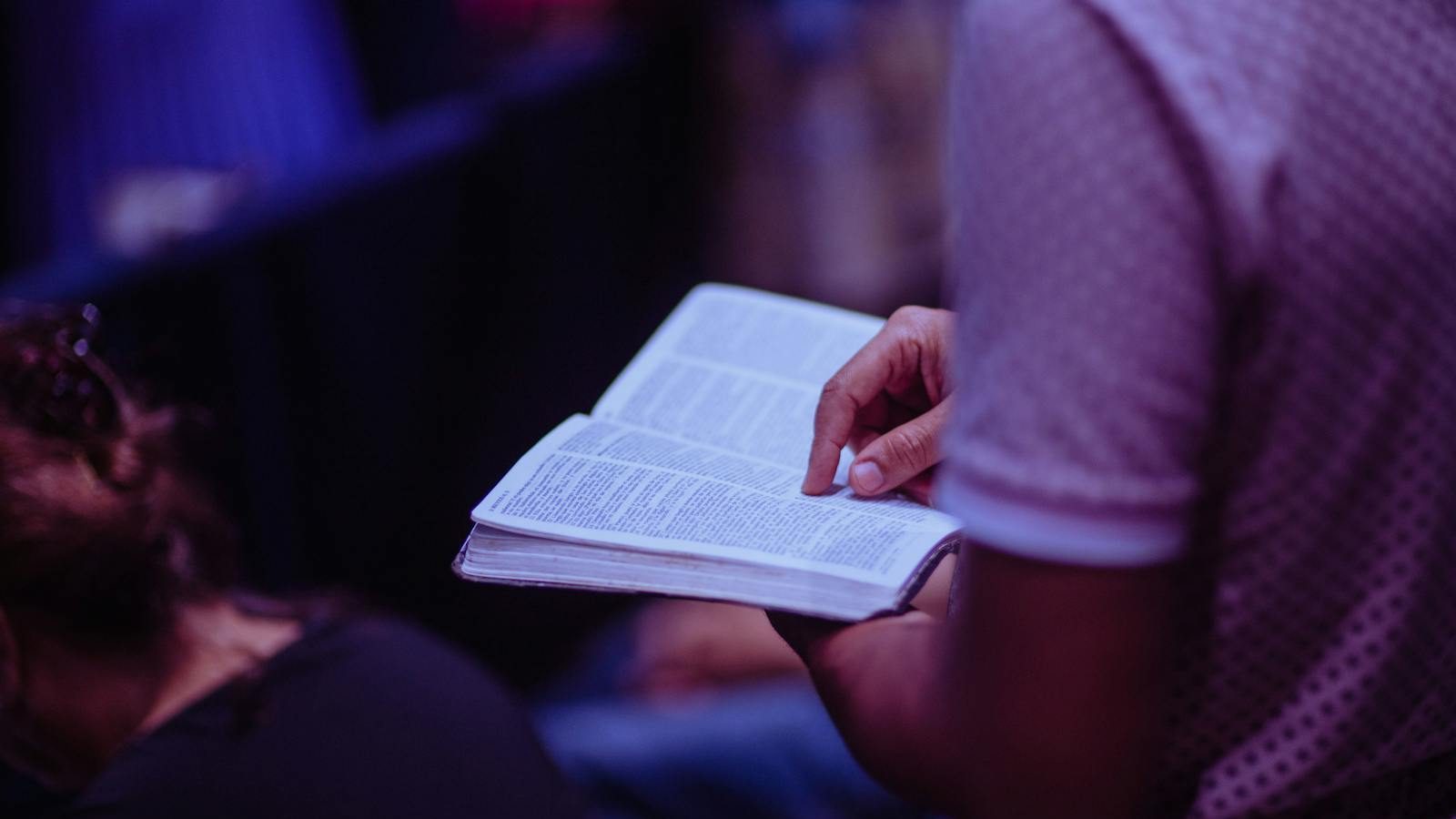 A focused moment of a person engaged in reading a Bible inside a church.