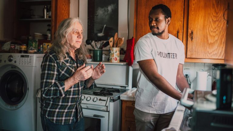 Two volunteers connect over cooking, fostering community spirit in a cozy kitchen setting.