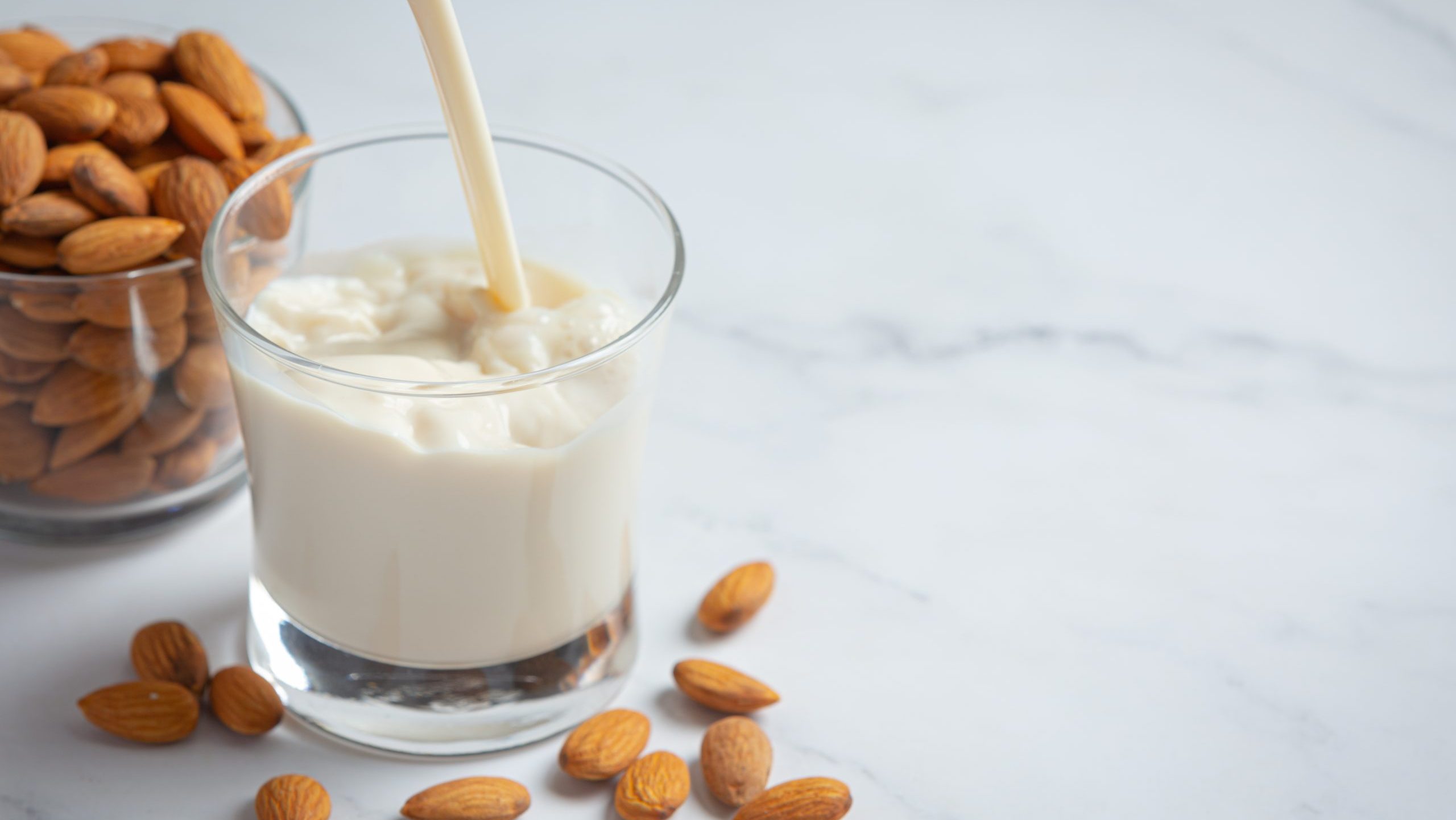 Almond milk with almond on marble background