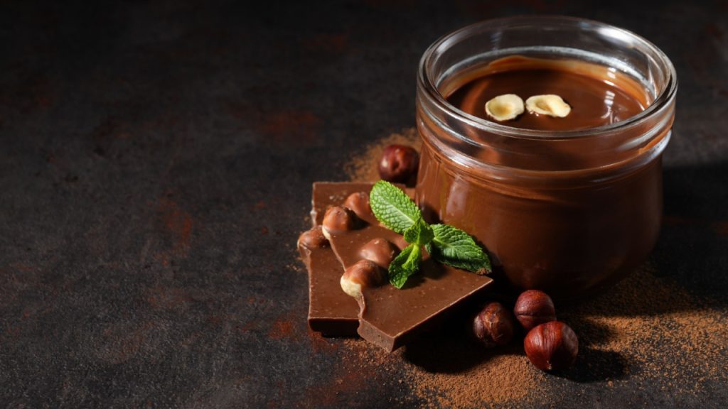 Chocolate paste in a jar with chocolate on a dark background