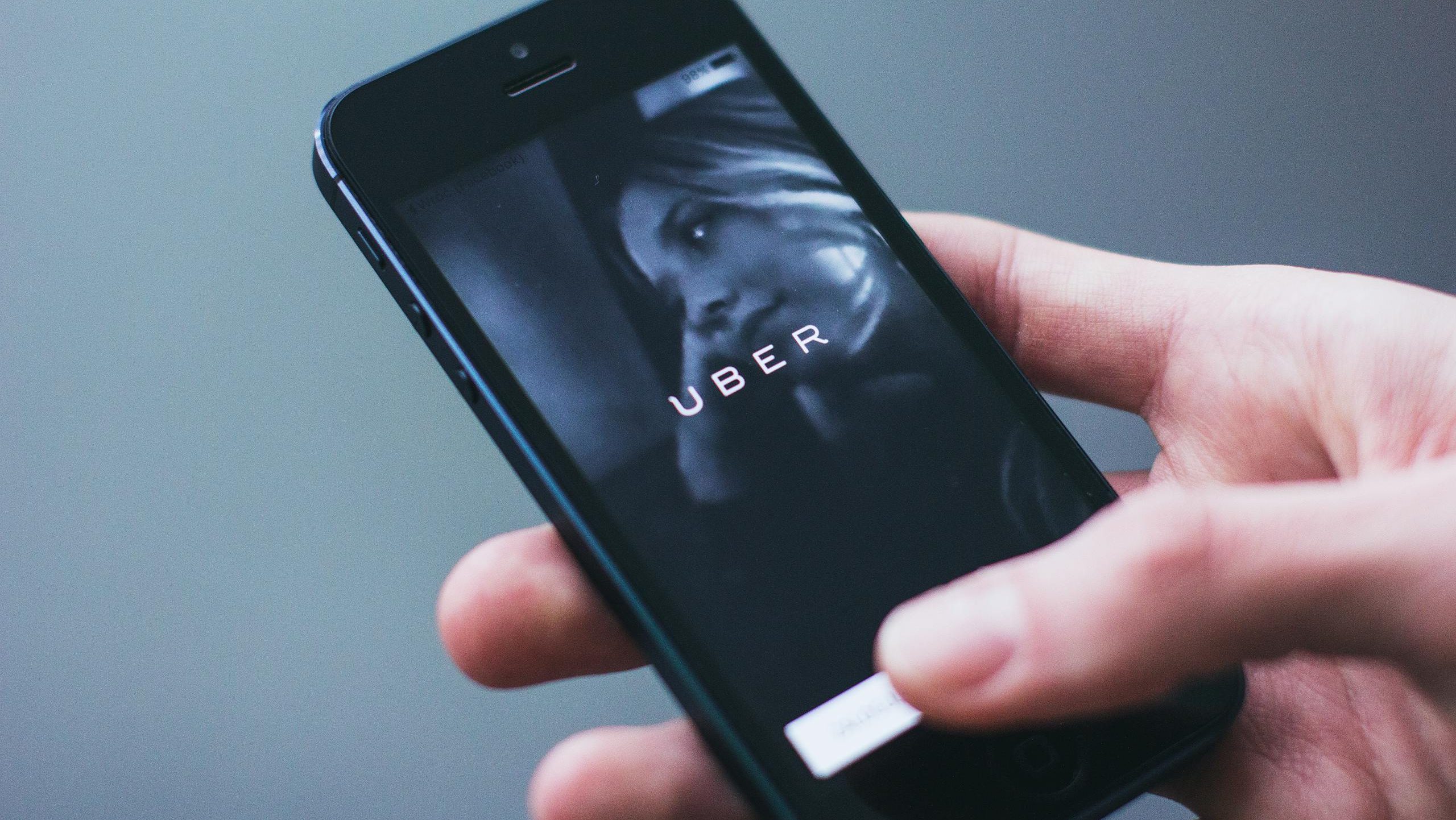 Close-up of a hand holding a smartphone with the Uber app open on the screen.