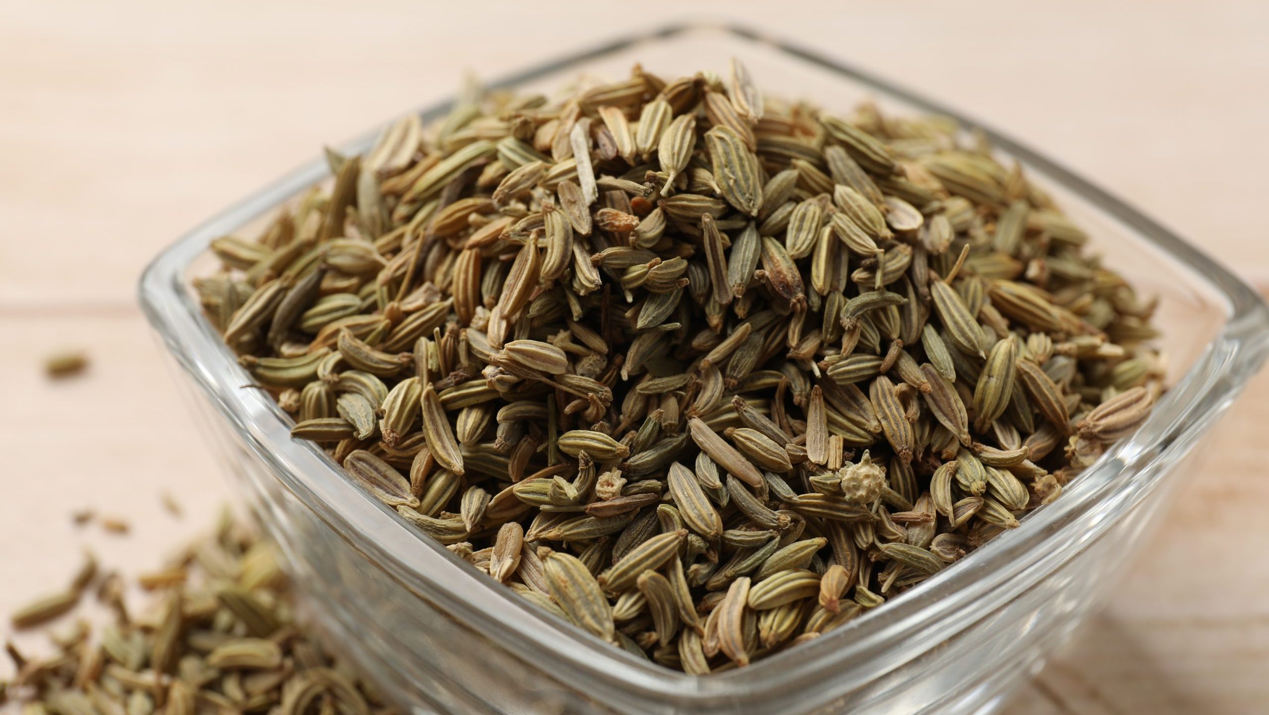 Fennel seeds in glass bowl on table, closeup