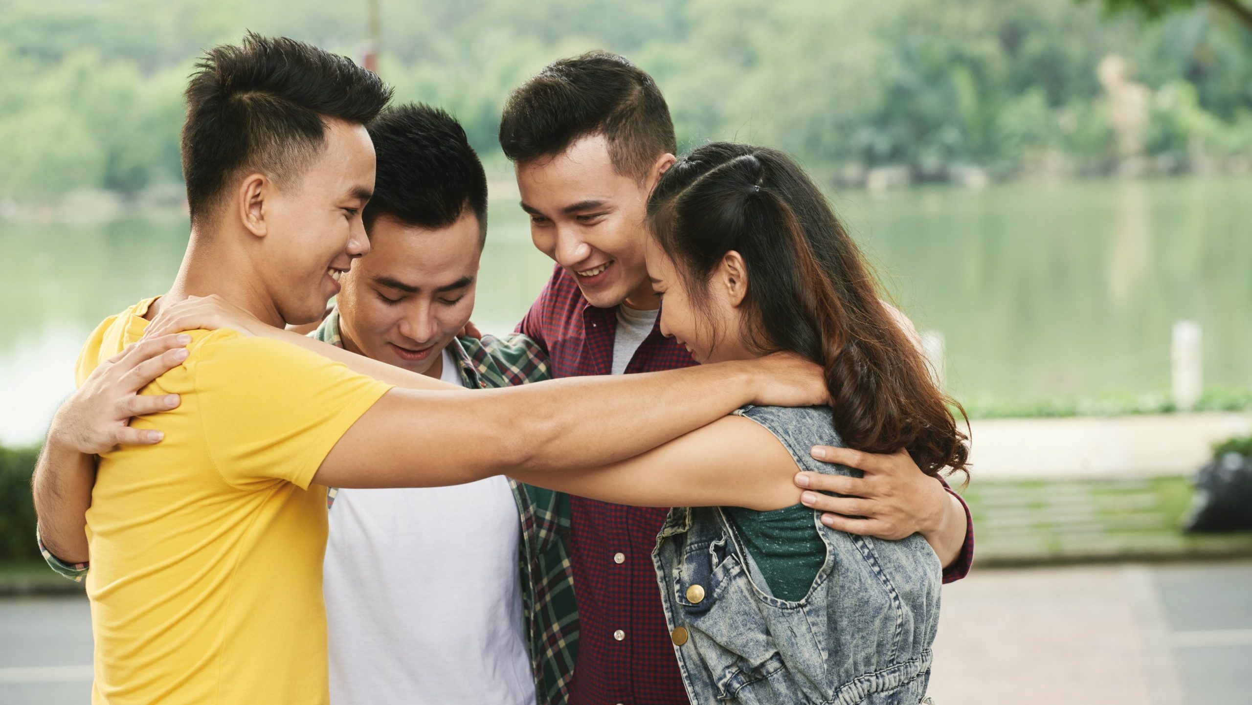 Group of hugging happy friends standing outdoors
