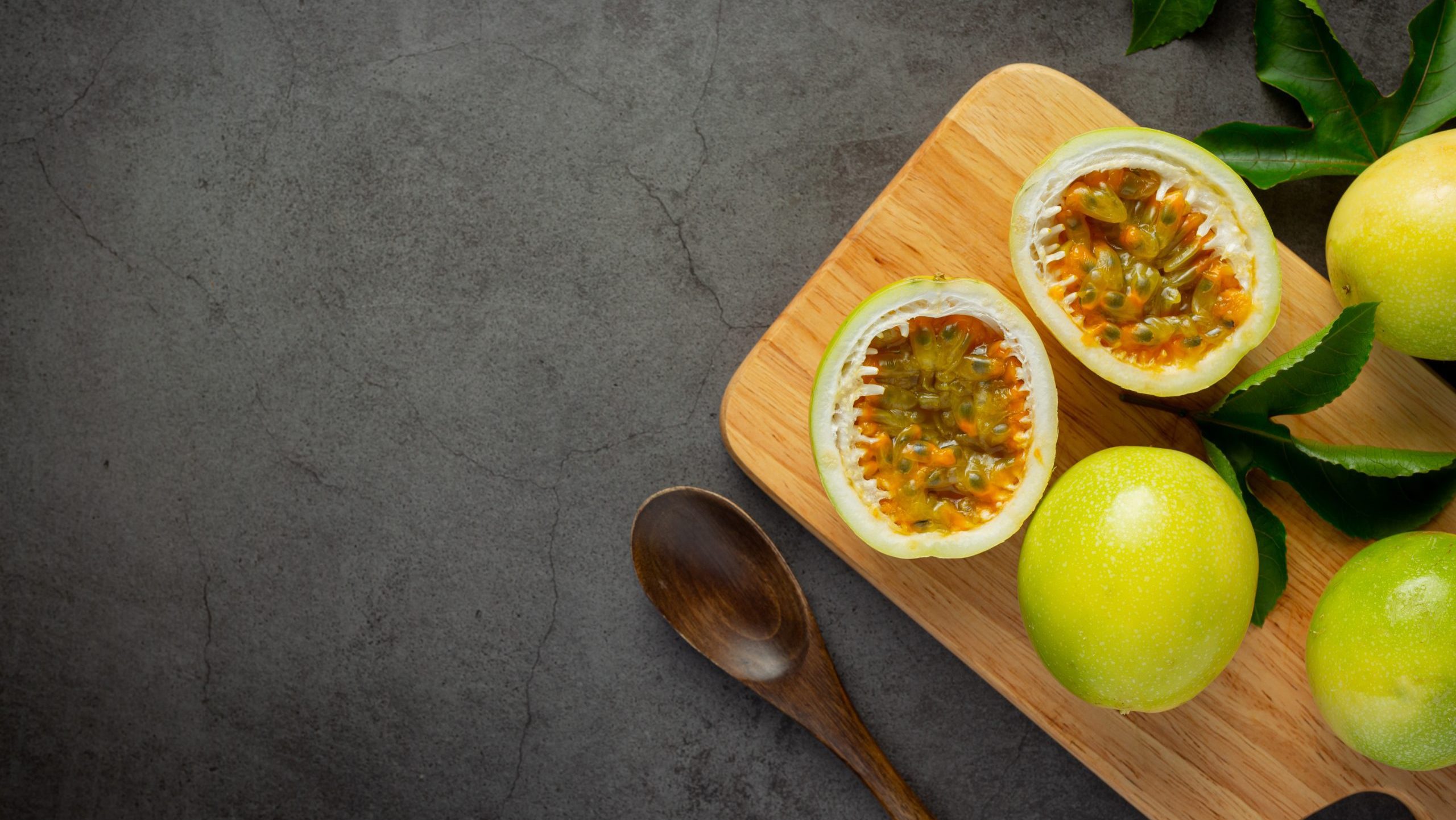fresh passion fruits cut in half place on wooden cutting board