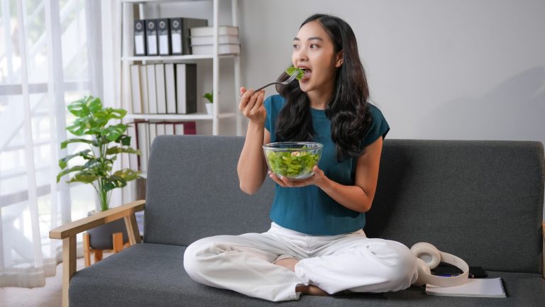 Young,Woman,Enjoying,A,Healthy,Salad,On,Her,Cozy,Sofa