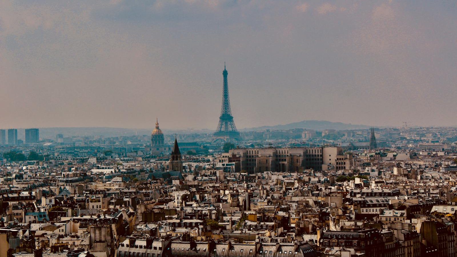 Explore the stunning panoramic cityscape of Paris with the iconic Eiffel Tower rising above the urban landscape.