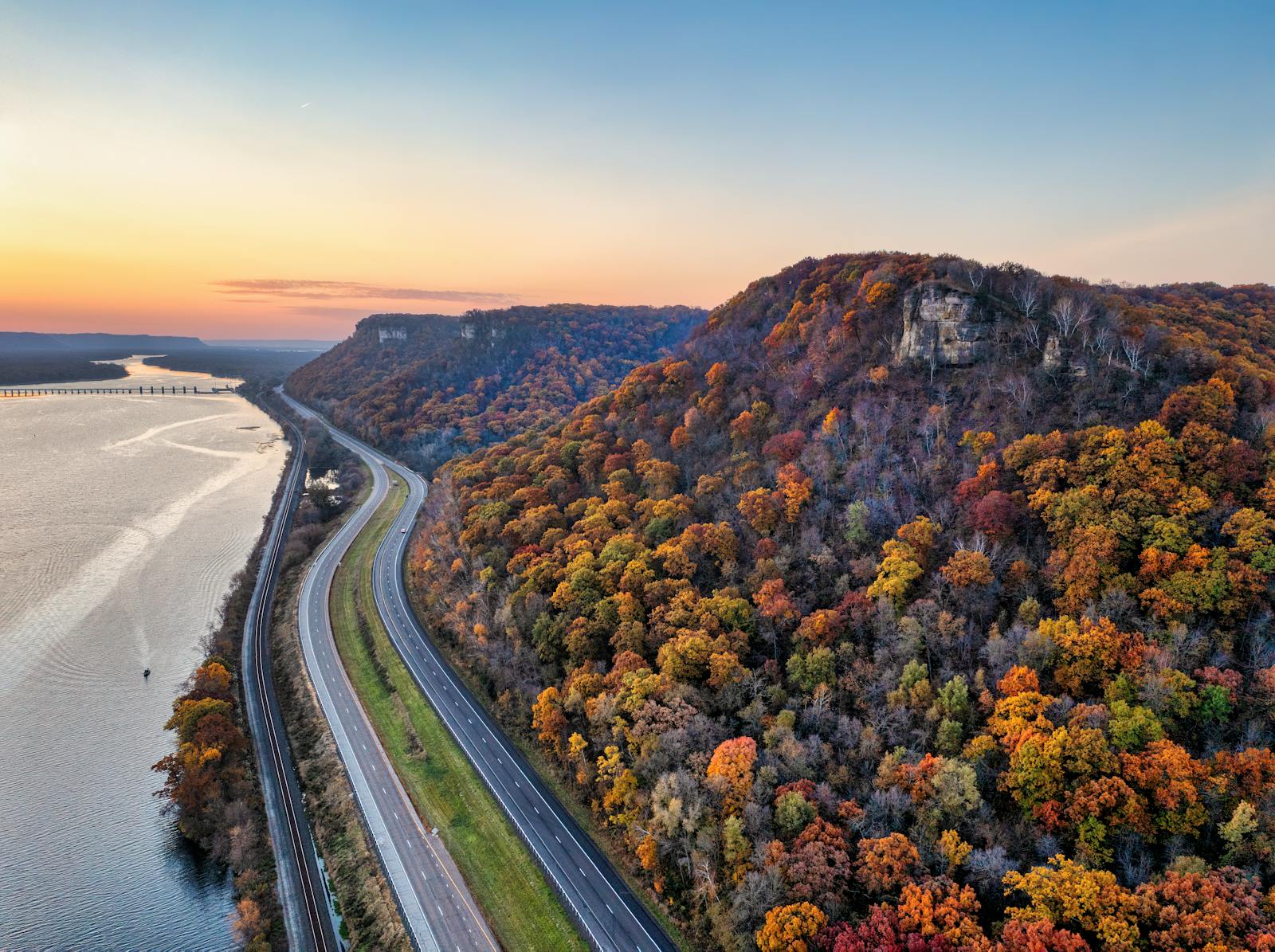 A stunning aerial view of a highway alongside a river with vibrant fall foliage in Minneiska, MN.