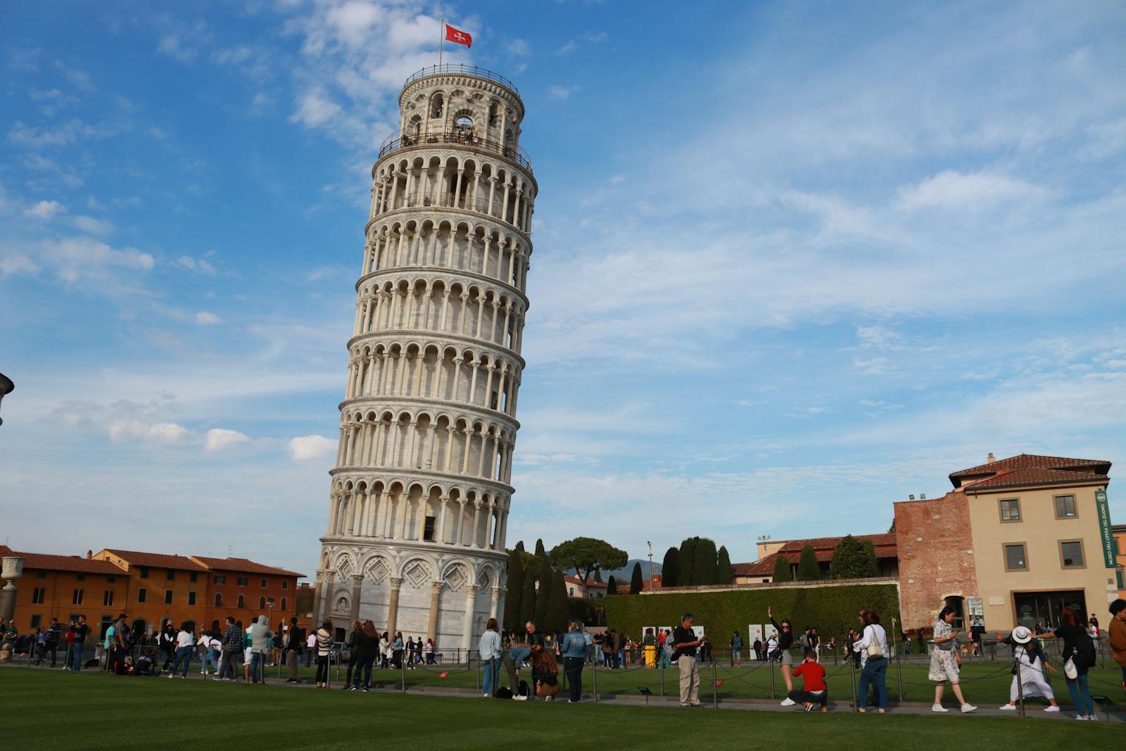 Iconic Leaning Tower of Pisa with tourists and blue sky backdrop.