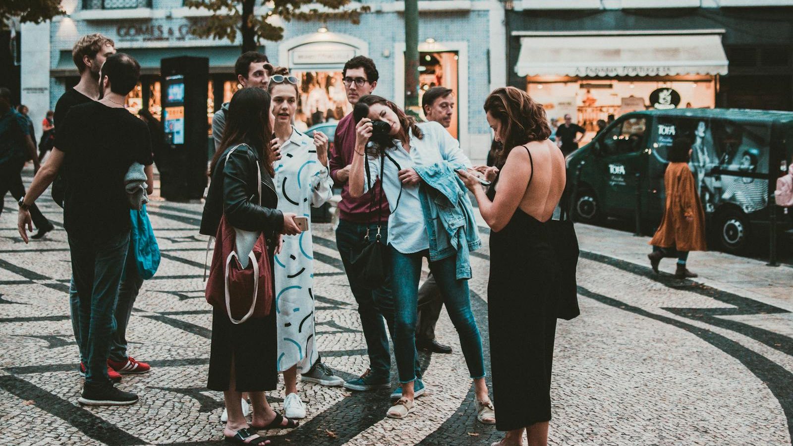 Casual group of tourists socializing and taking photos on a bustling European street.
