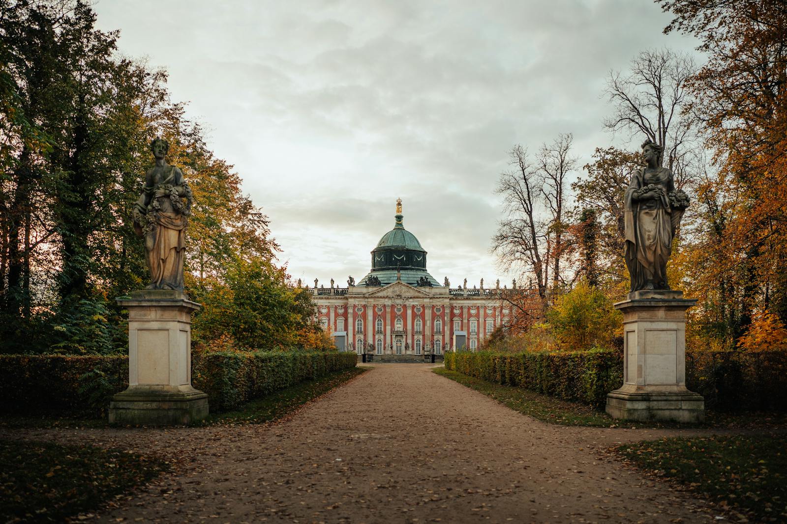 Scenic view of New Palace in Potsdam surrounded by trees and statues during autumn.