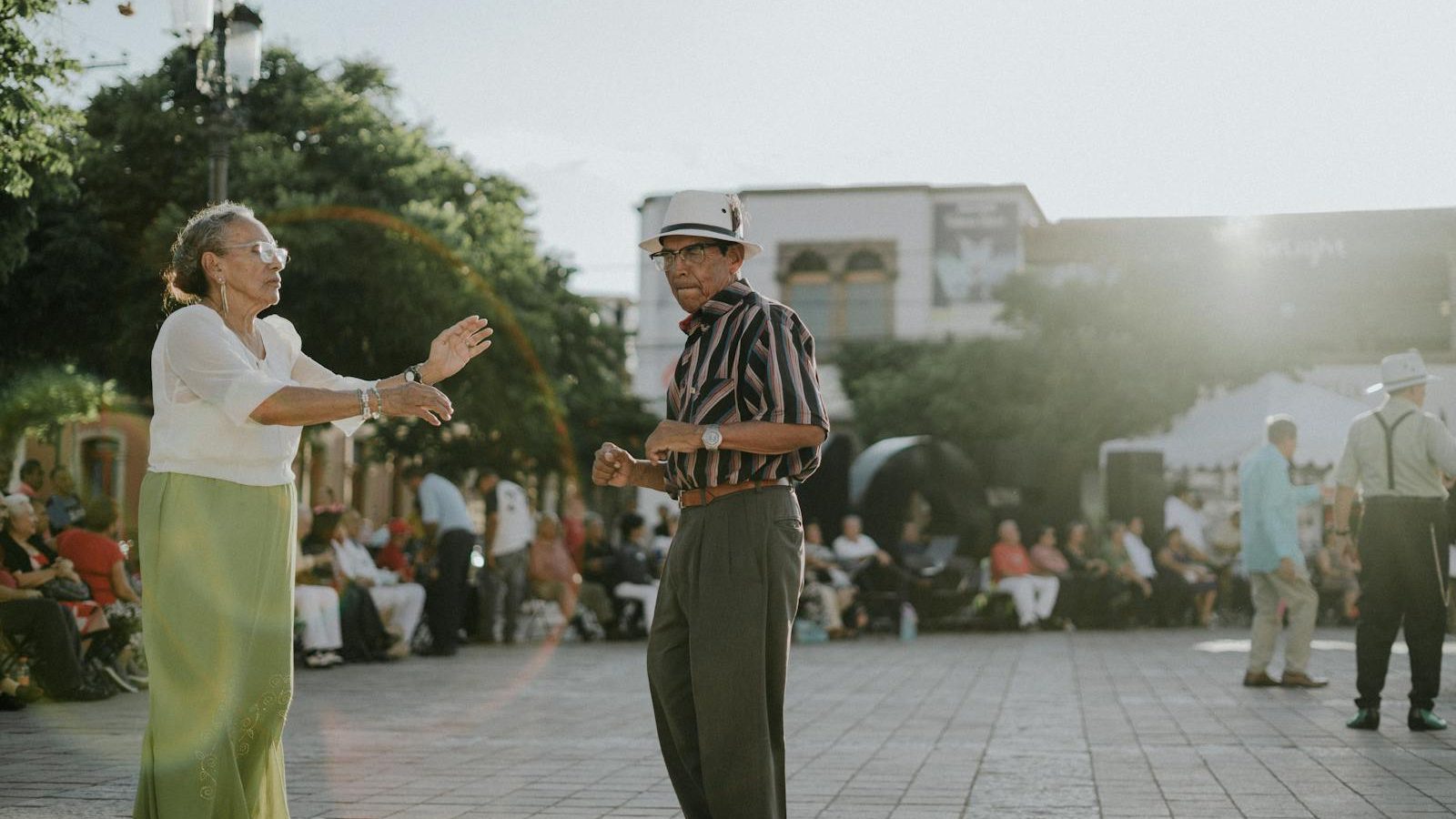 Elderly couple dancing in sunlit León de los Aldama plaza, showcasing joy and community spirit.