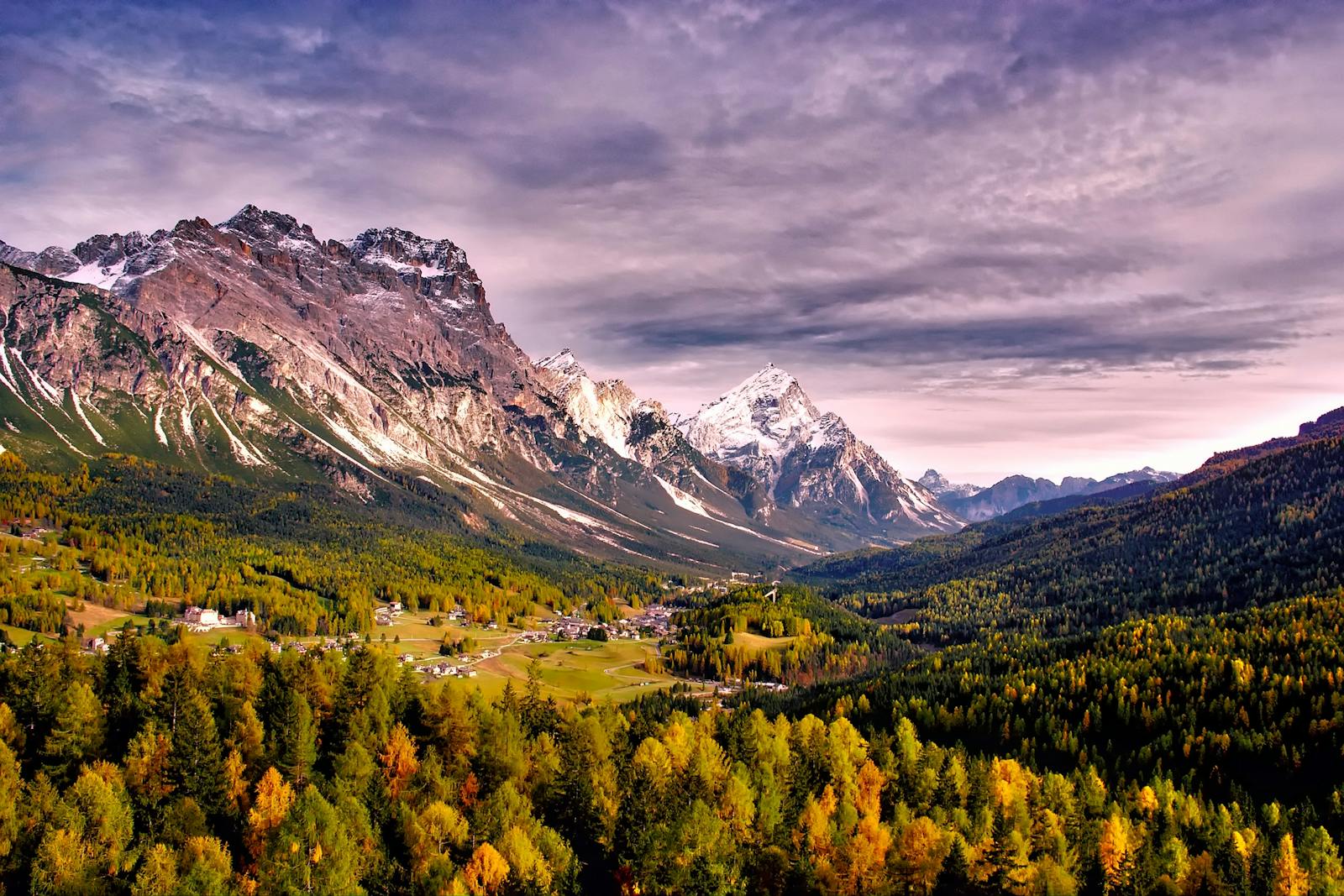 Stunning autumn view of alpine mountain range with colorful forest and scenic valley.