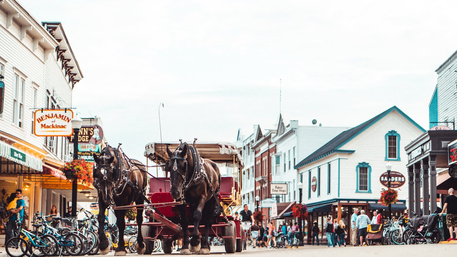 A bustling Mackinac Island street scene featuring a horse-drawn carriage and vibrant architecture.