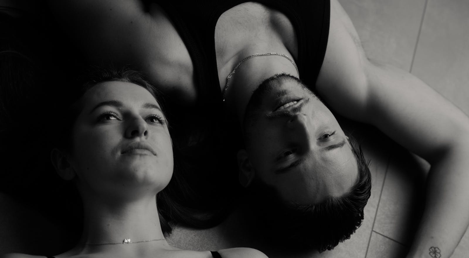 Intimate black and white portrait of a couple lying on the floor, expressing tenderness and serenity.