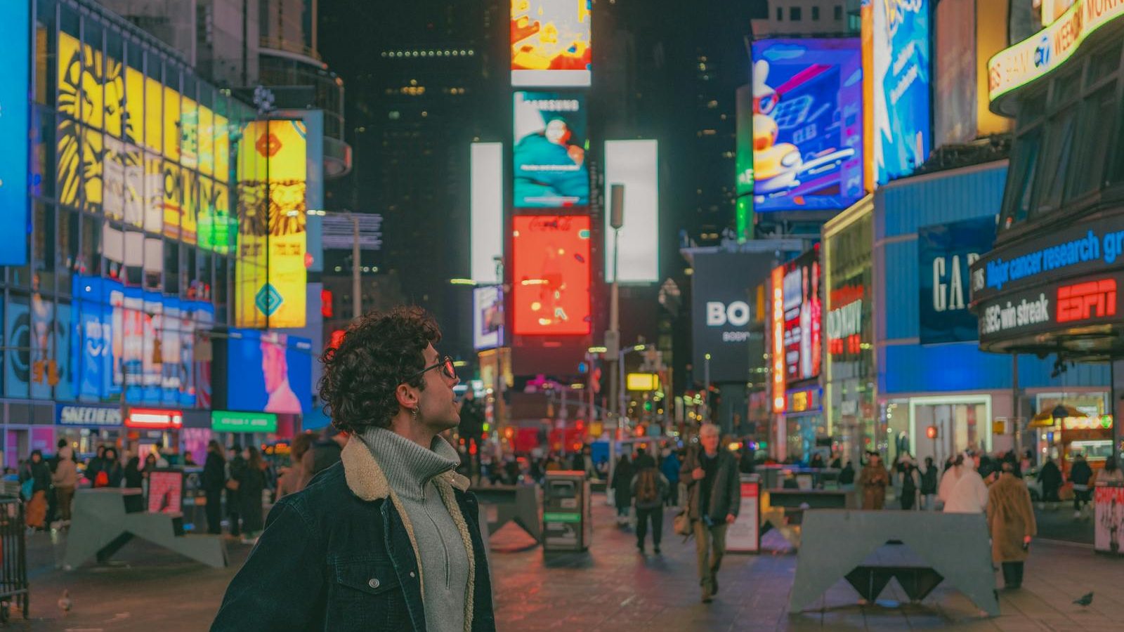Explore the bustling energy of Times Square at night with vibrant lights and diverse crowds.