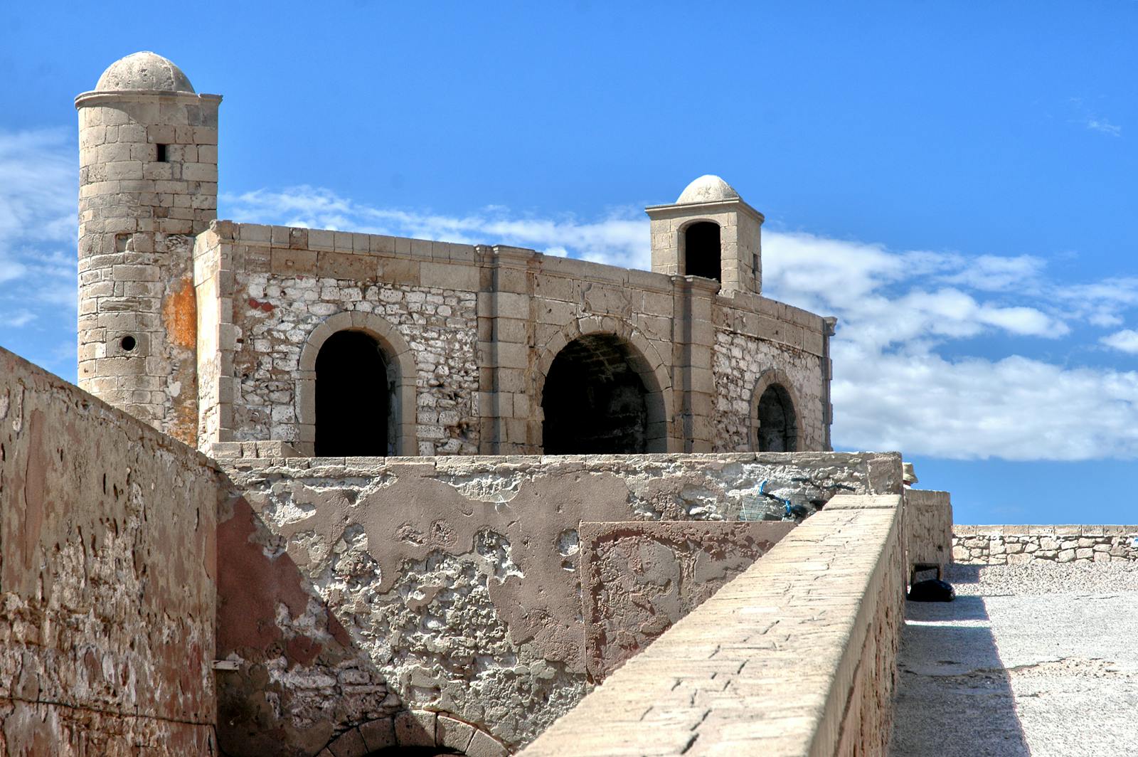 Explore the historic fortress walls of Essaouira, Morocco, against a vibrant blue sky.