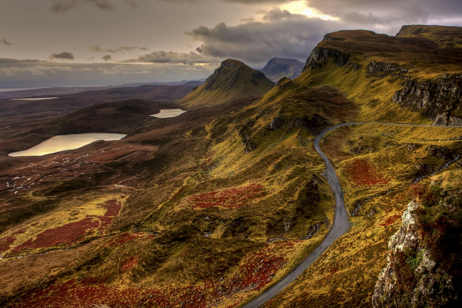 Breathtaking view of the Scottish Highlands with winding roads and serene lakes under a dramatic sky.