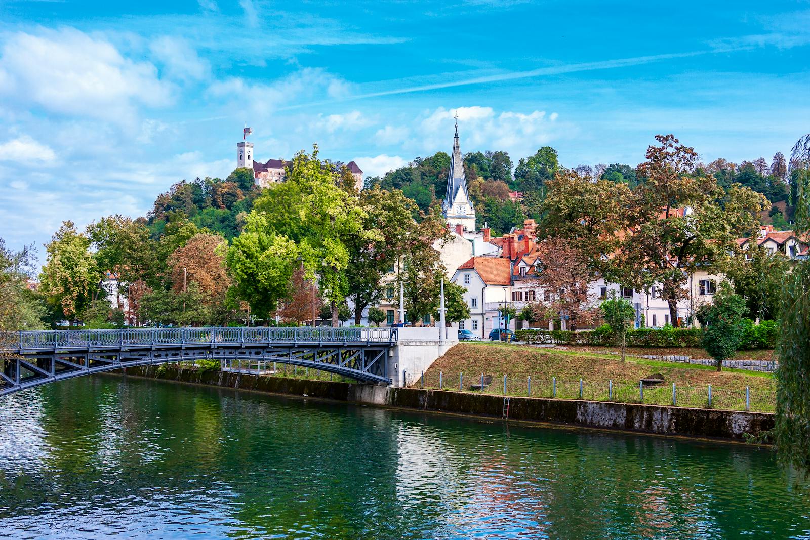 Picturesque scene of Ljubljana's river and historic architecture under a bright sky.