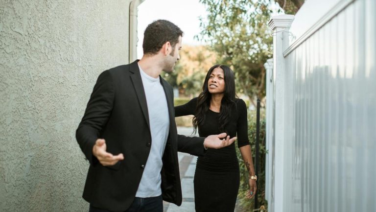 A couple arguing in an outdoor narrow passageway, showcasing relationship tension.