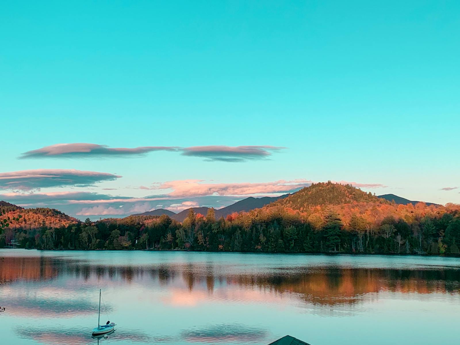 Breathtaking autumn landscape of Lake Placid with reflections and a sailboat.