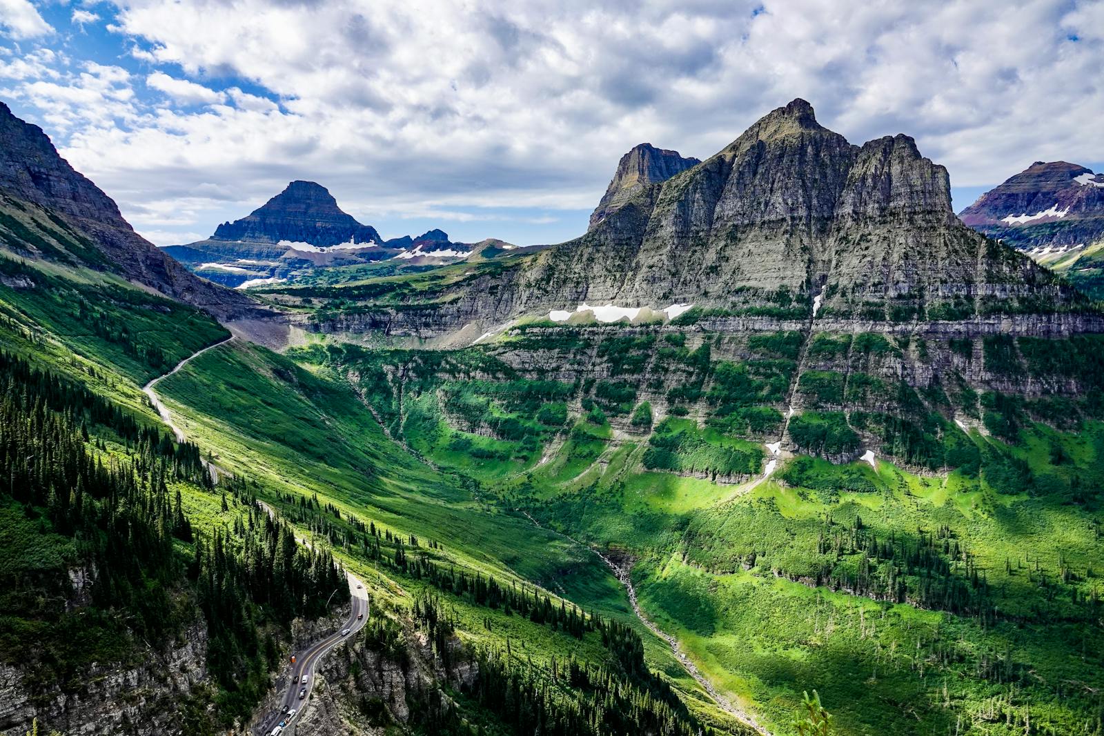Breathtaking view of mountains and valleys in Glacier National Park under a vibrant sky.