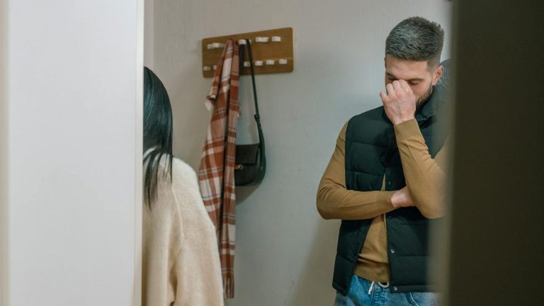 A man and woman argue in a domestic setting, showcasing tension and sadness.