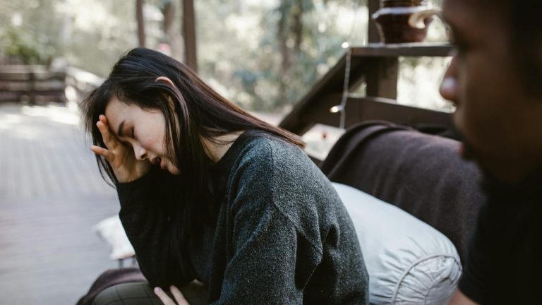 A troubled couple sits outdoors during a deeply emotional conversation.