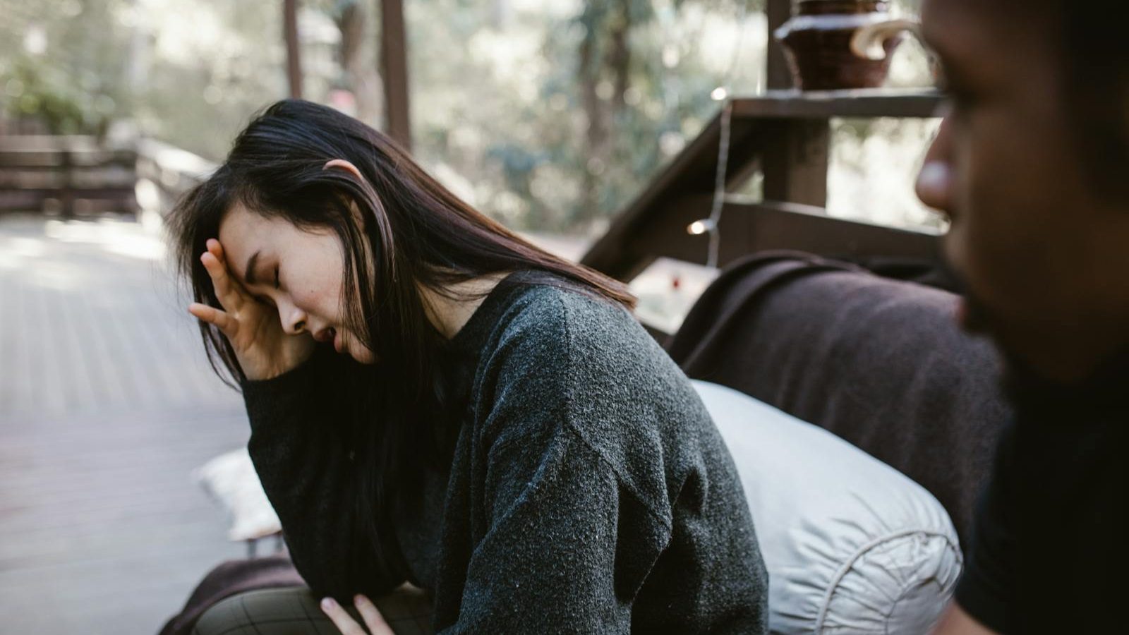 A troubled couple sits outdoors during a deeply emotional conversation.
