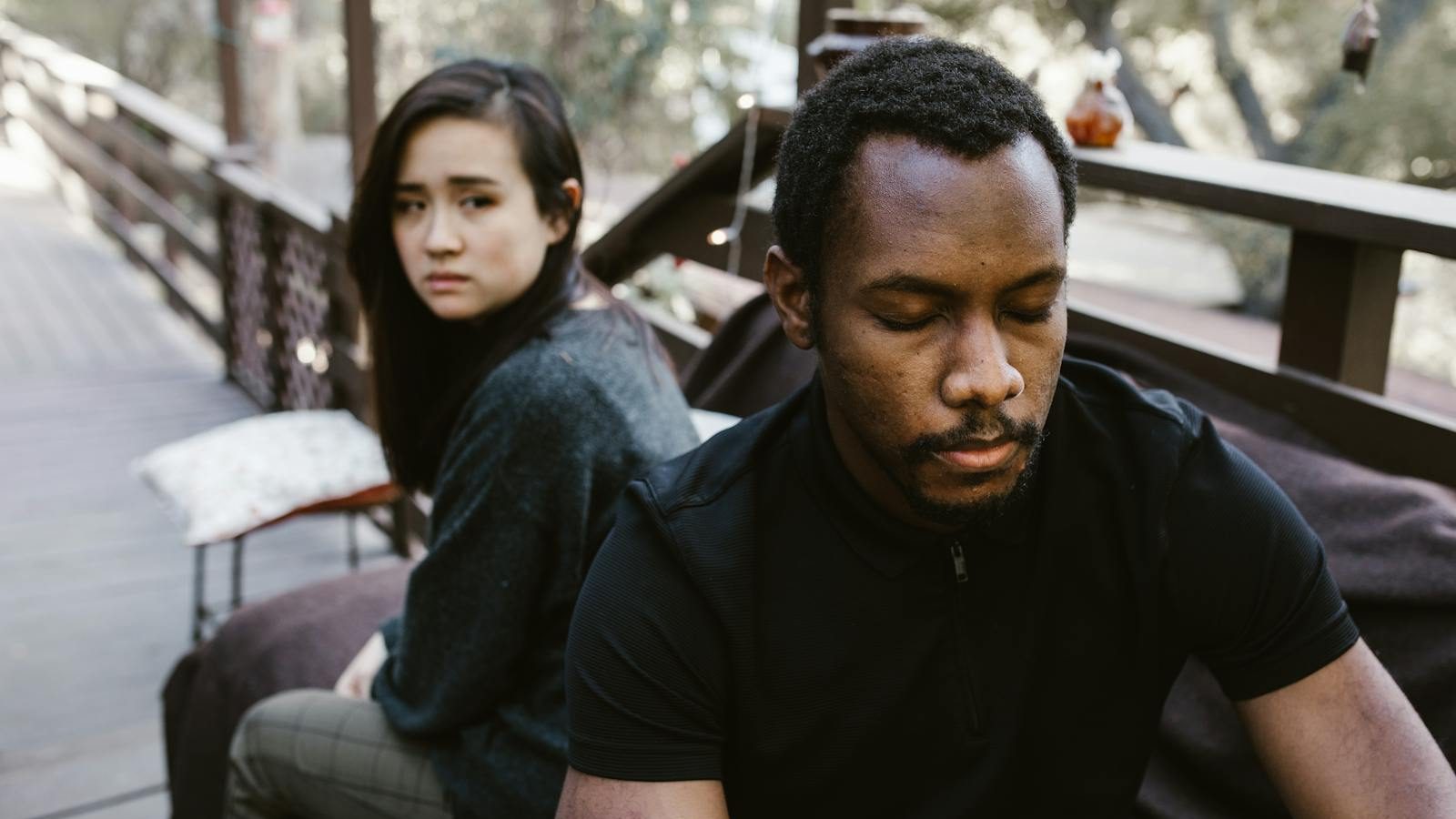 A couple in a serious moment, suggesting conflict or breakup, outdoors.