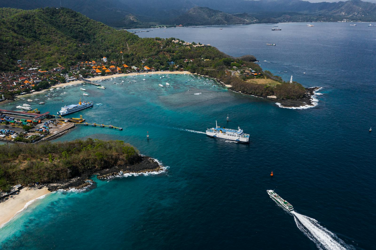 Stunning aerial view of Bali's coastline, showcasing ferries on crystal blue waters. Perfect for travel inspiration.