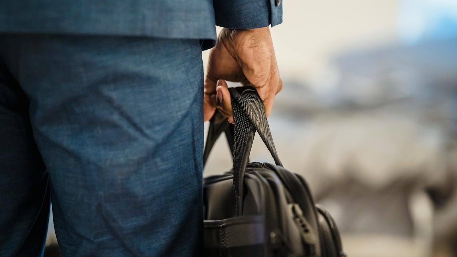 Close-up of a businessman's hand holding a briefcase, symbolizing professionalism.