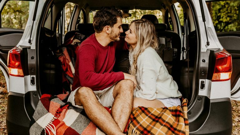 man and woman sitting on car's trunk