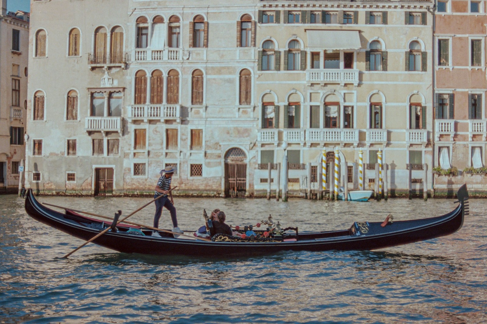 A man riding a boat down a river next to tall buildings