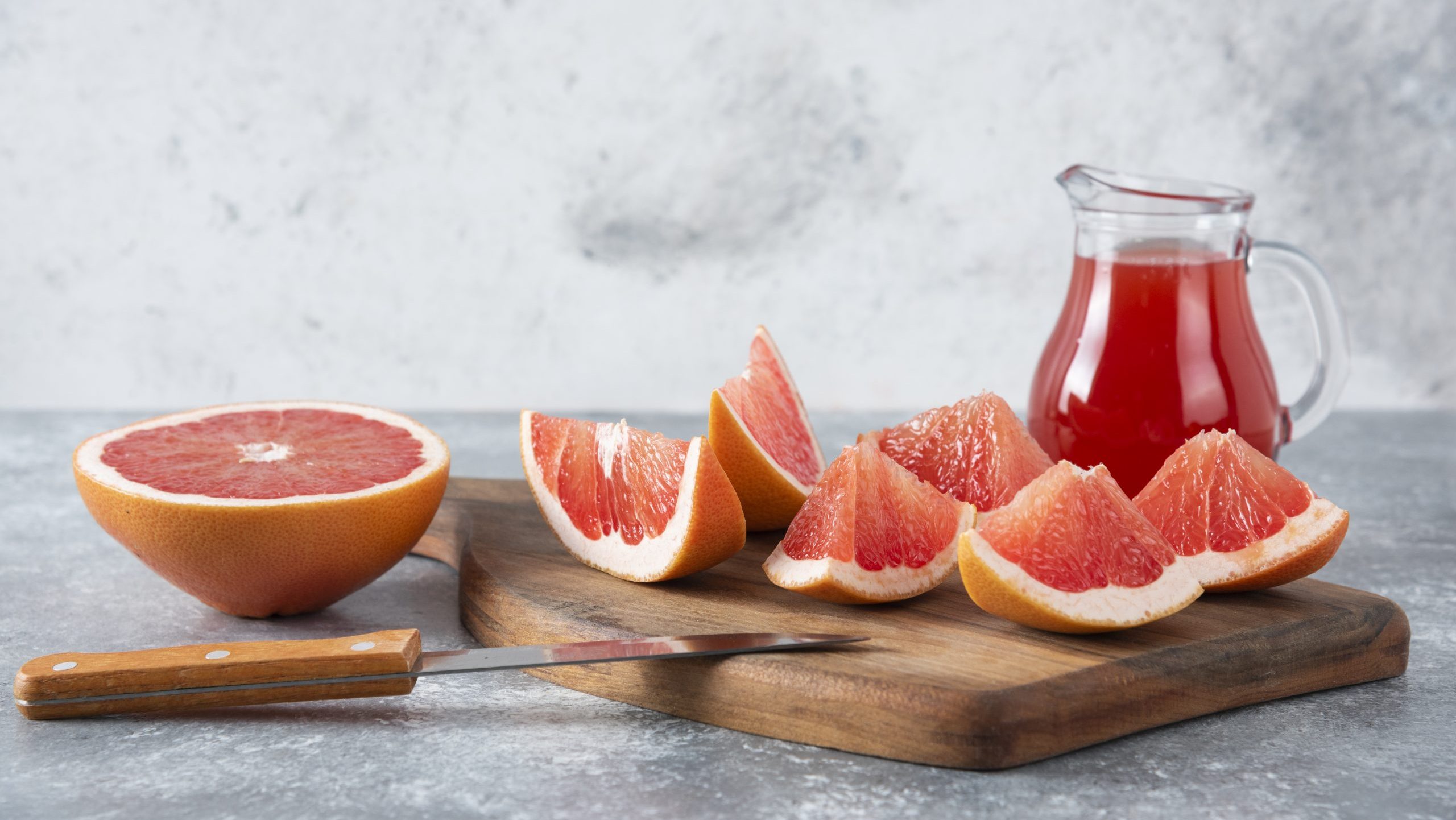 Glass pitcher of fresh grapefruit juice with slices of fruits . High quality photo