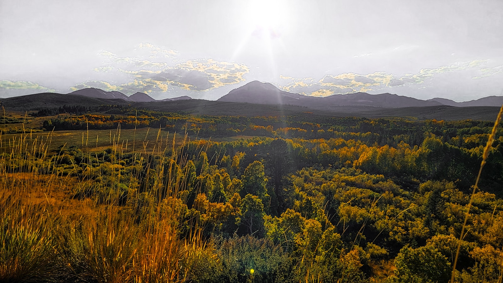 The sun shines brightly on the mountains in the distance