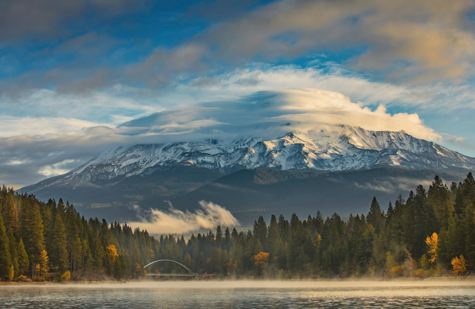 a lake with trees and mountains in the background
