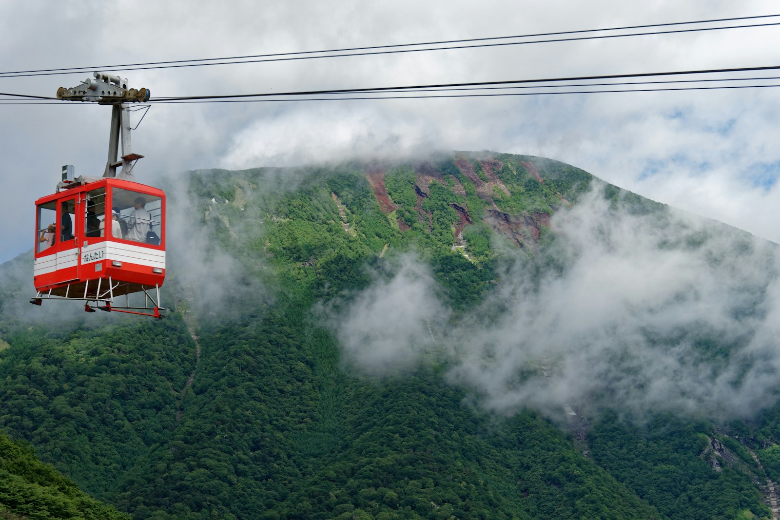 a red and white gondola with a mountain in the background
