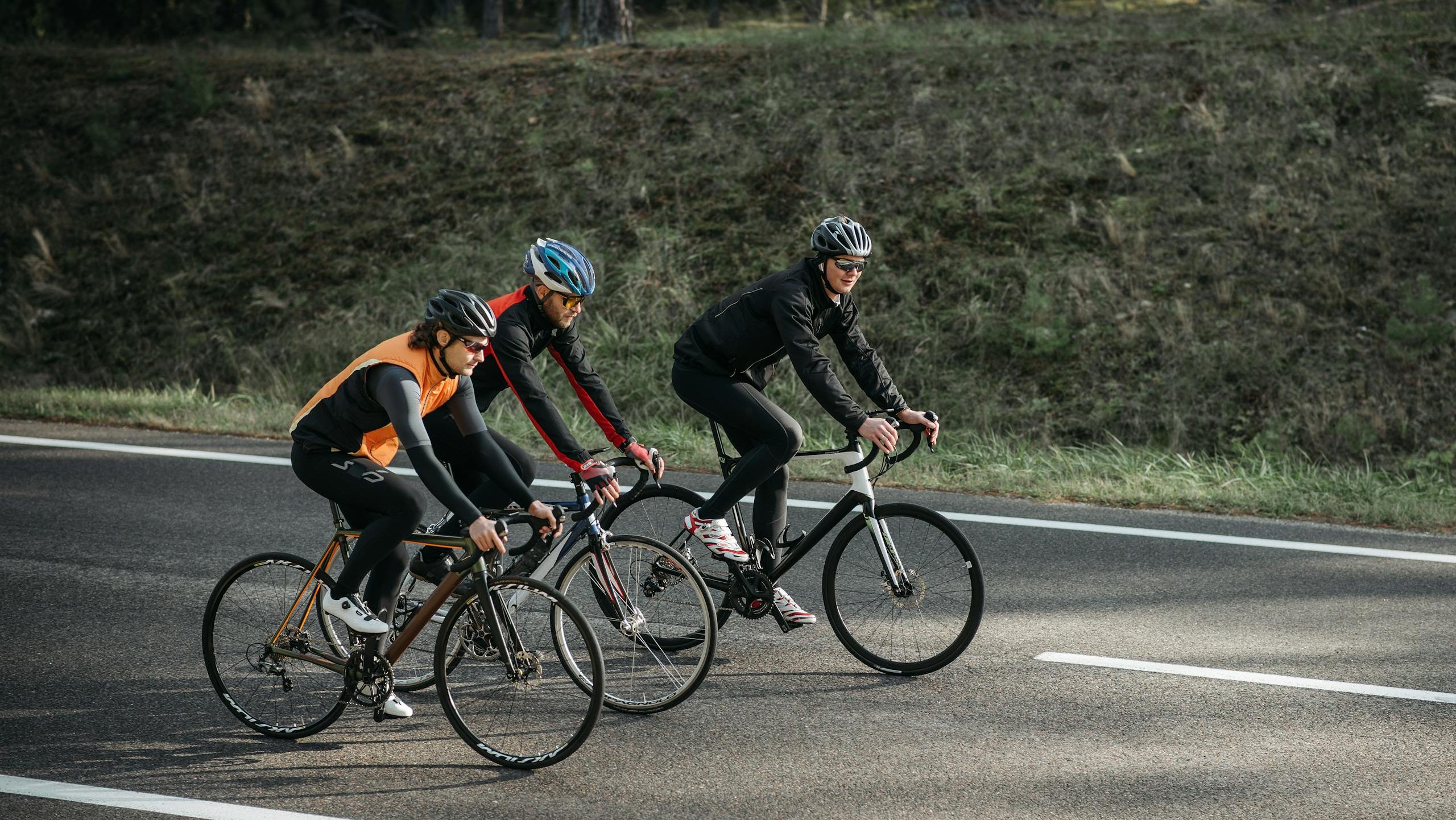 Three cyclists riding bikes on an open road, enjoying outdoor exercise and leisure activity.