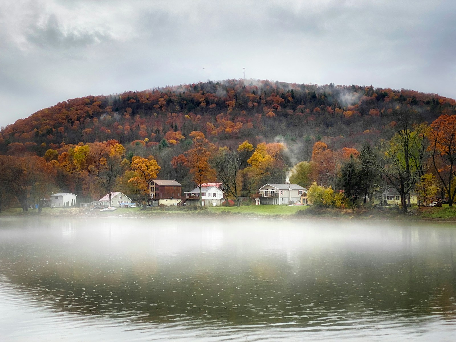 a body of water with houses on a hill in the background