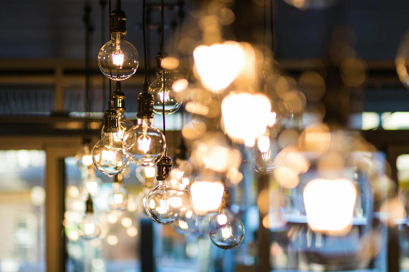 A modern and ambient urban setting with glowing, hanging light bulbs in focus.