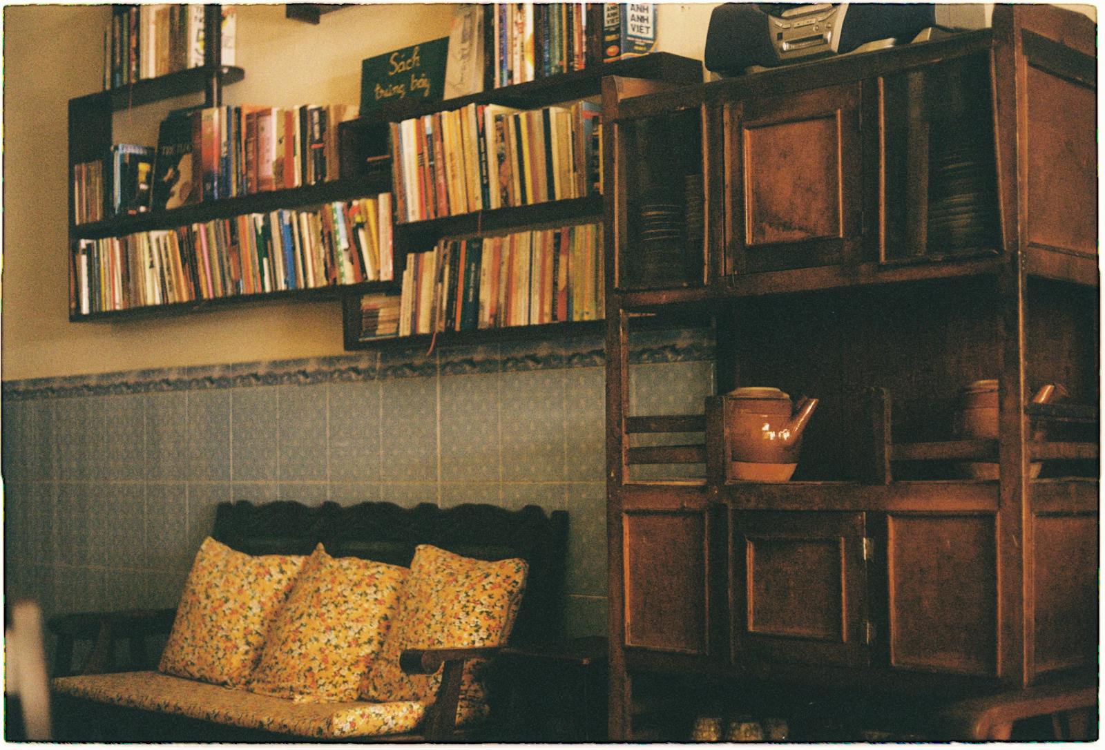 A warm, vintage room featuring bookshelves, a wooden bench, and old cupboards.