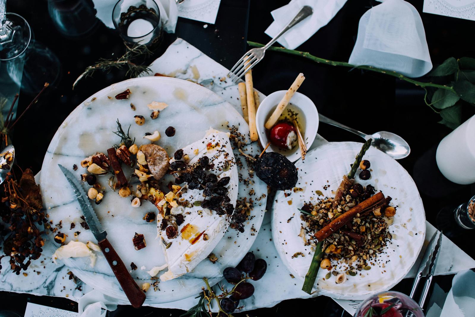 From above of plates with remains of various dishes left after festive dinner on table with cutlery and flowers