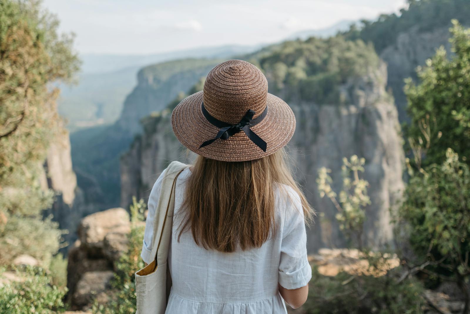 A woman in a hat enjoys the breathtaking view of a canyon, capturing the essence of adventure and travel.