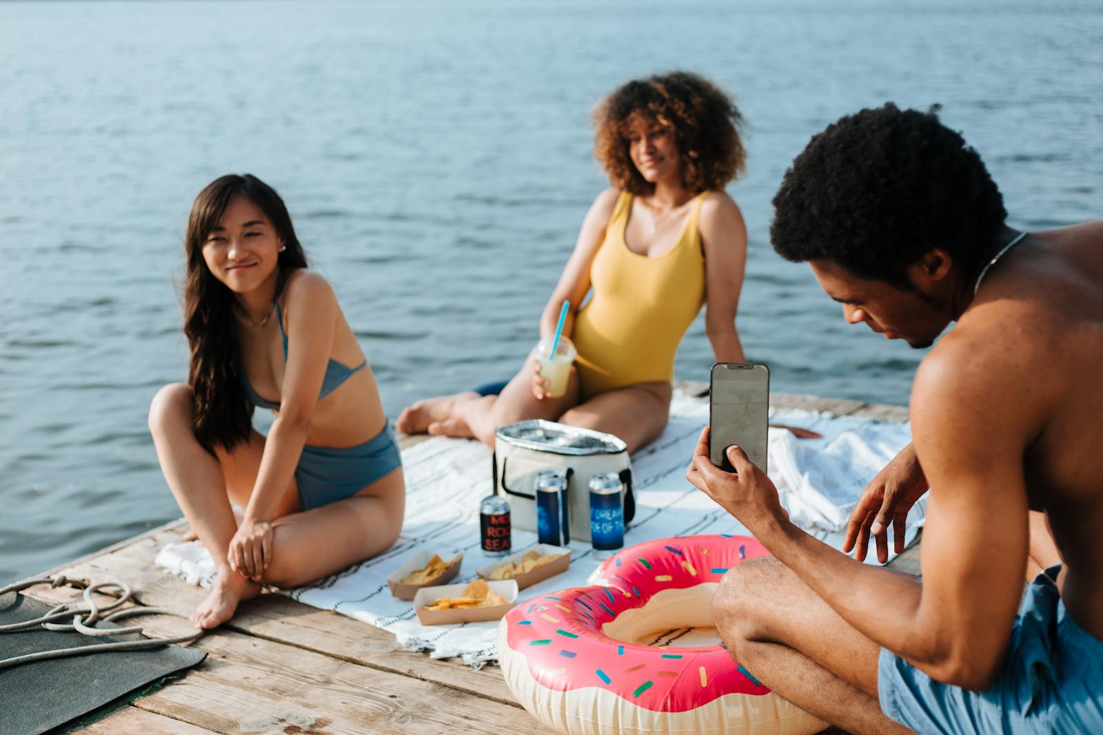 Group of diverse friends relaxing by the lake, enjoying summer vibes.