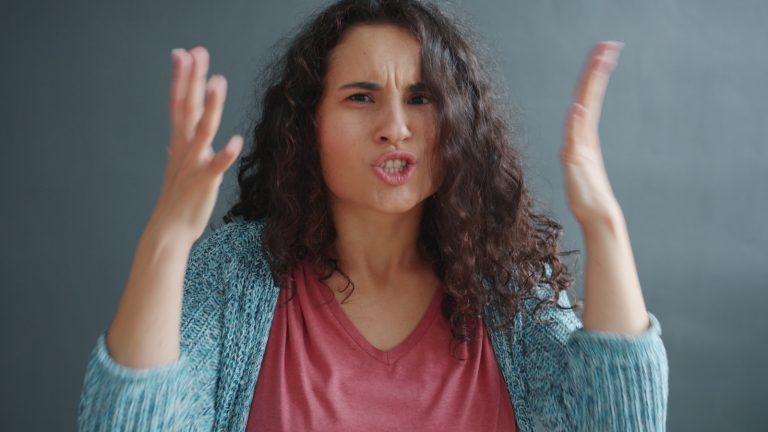 Woman with curly hair looking angry and frustrated.