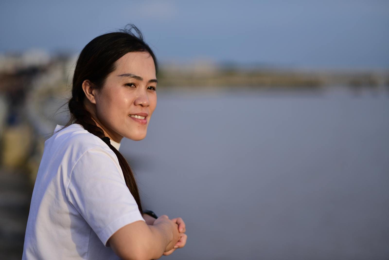 Smiling woman enjoying a day by the water with a serene and peaceful atmosphere.