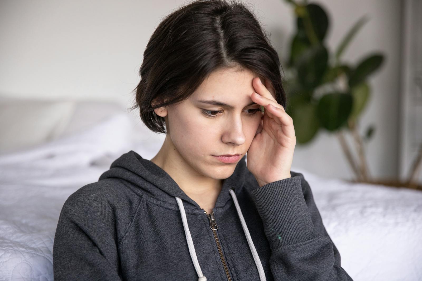 Young woman in a hoodie appearing thoughtful and pensive, captured indoors.