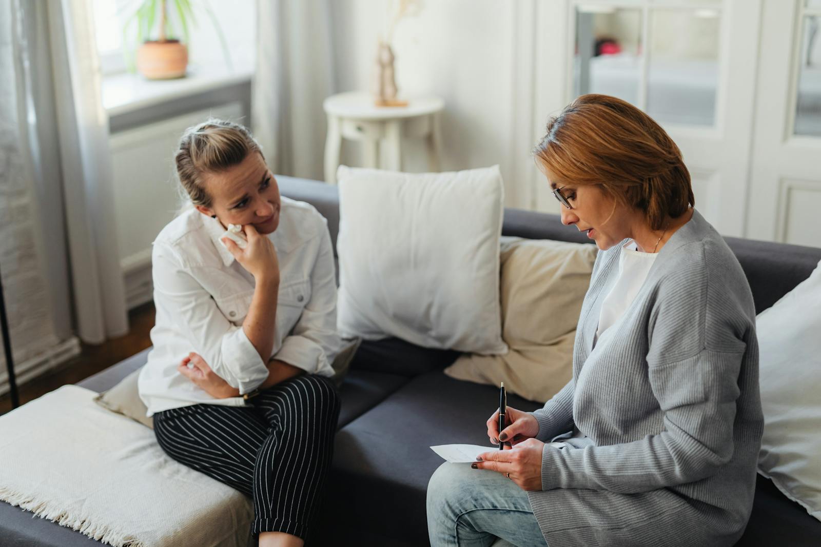 A thoughtful therapy session between two women in a cozy room.